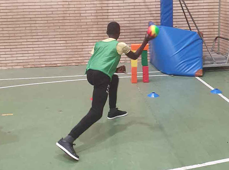 Alumno tirando totems con pelota arcoíris