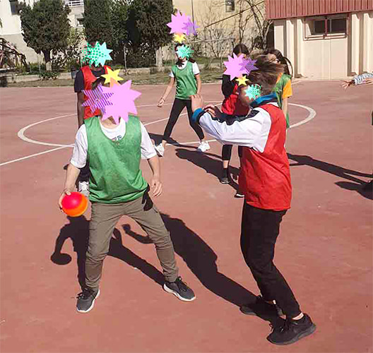 Alumnos jugando con pelota arcoíris